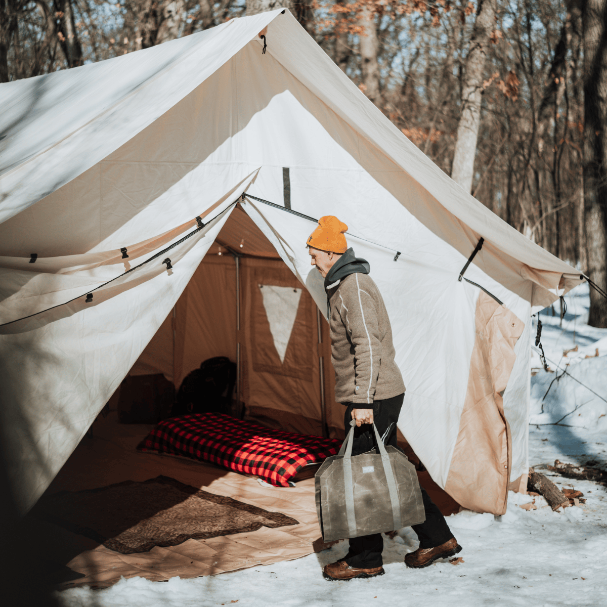 alpha wall tent set up in the snow with a man going inside it