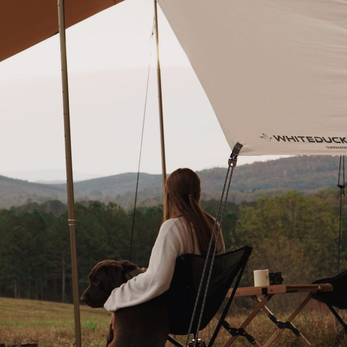 a girl sitting under the sunshade tarp with her dog enjoying the weather