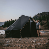 10 regatta bell tent night sky in front of lake with fairy lights and woman holding lantern in front