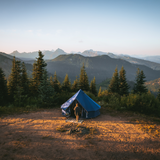 10' Regatta Bell Tent - Sapphire Blue placed in a forest with a man walking into it