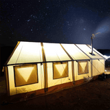 alpha wall tent glowing at night with lights on inside the tent and a chimney coming out of the stove jack