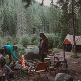 rover scout tent set in forest with three men sitting on chairs across a bonfire