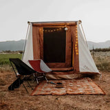 a cabin tent setup in a desert with chairs and rug
