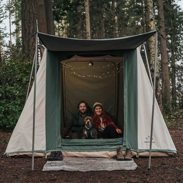 couple enjoying nature in a cabin tent with their dog