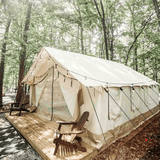 alpha wall tent set up in the forest on a platform