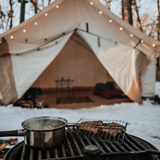 alpha wall tent set in the snow with a bbq grill outside