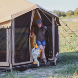 Altimus bell tent placed outdoors with a woman and her husky coming out of it to play