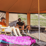 altimus bell tent set up outdoors with its mesh closed and two men enjoying their drinks sitting inside