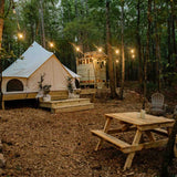 avalon bell tent placed on a platform in the outdoors with a table in front of it