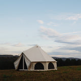 avalon bell tent placed on the grass outdoors with flaps opened and mesh closed