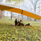 A couple is having drinks under the sunshade tarp.
