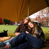 A couple is resting together under the sunshade tarp.
