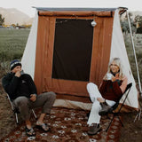 couple enjoying coffee in a cozy atmosphere in front of a cabin tent