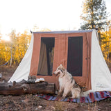 dog sitting in front of a cabin tent  