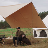man with his dog sitting under the sunshade tarp in front of avalon bell tent