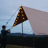 A man setting up his sunshade tarp and adding fairy lights on it as well