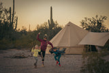 mother and her kids playing outside with a regatta bell tent set with bell tent awning behind them